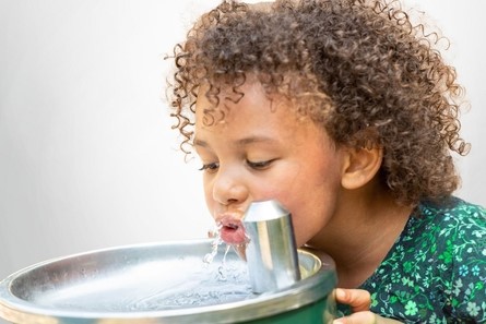 child drinking from water fountain